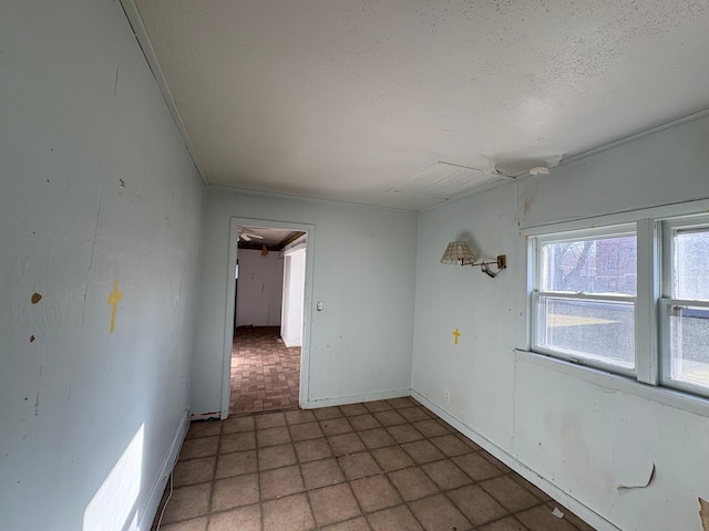 spare room featuring a textured ceiling, baseboards, and brick patterned floor