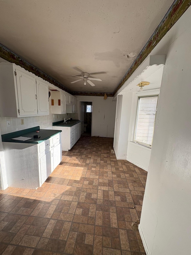 kitchen featuring ceiling fan, white cabinetry, brick patterned floor, and a wealth of natural light