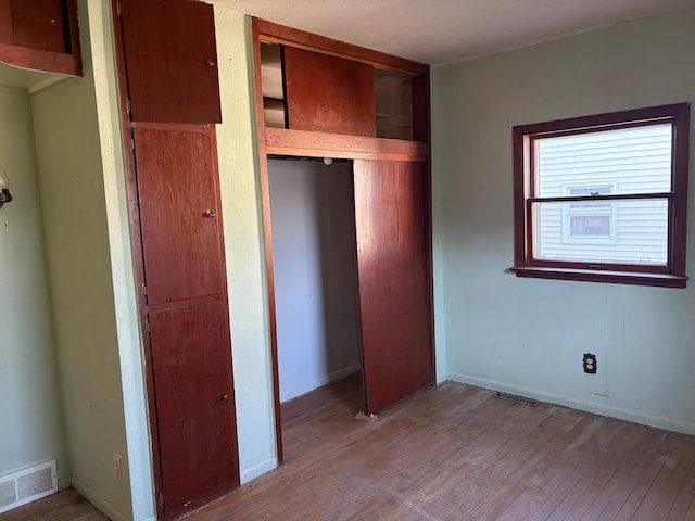unfurnished bedroom with a closet, light wood-style floors, and visible vents