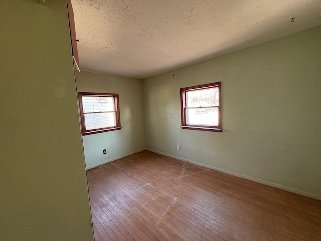 unfurnished room with a textured ceiling, baseboards, and hardwood / wood-style floors