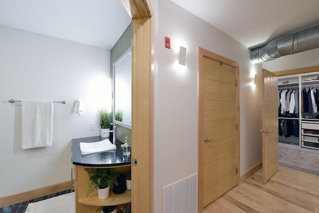319 Broadway N Unit 202, Fargo, ND 58102 - bathroom featuring wood finished floors, vanity, and a walk in closet