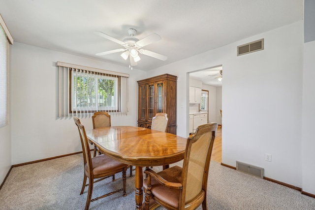 dining space featuring ceiling fan, light colored carpet, and baseboards