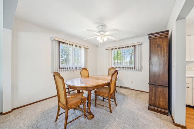 dining area with ceiling fan, light carpet, and baseboards