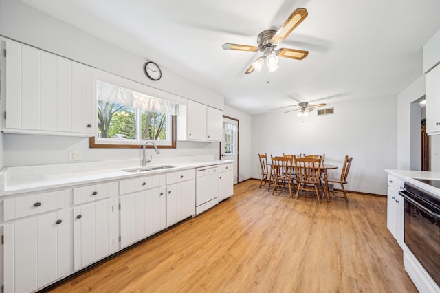 kitchen with a sink, dishwasher, range with electric cooktop, light wood-style floors, and light countertops