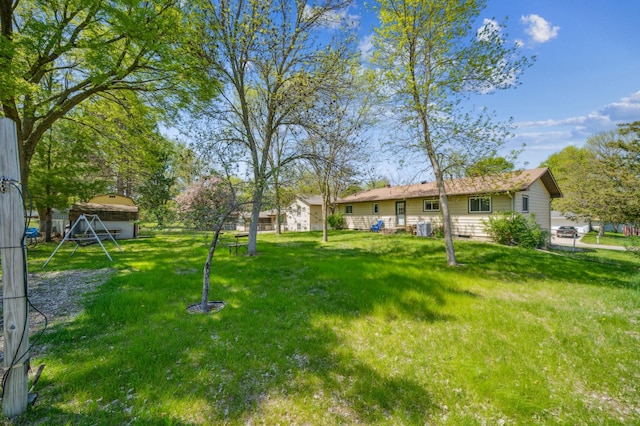view of green lawn with central AC unit