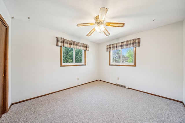 carpeted empty room featuring baseboards and a ceiling fan