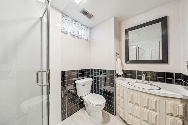 full bathroom with toilet, tile walls, a shower stall, vanity, and a wainscoted wall