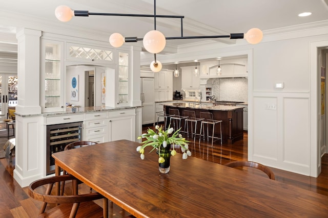 4812 Maple Rd, Edina, MN 55424 - dining room with beverage cooler, ornamental molding, dark wood-type flooring, a decorative wall, and decorative columns