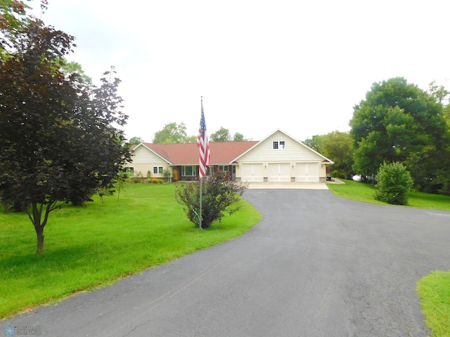 ranch-style home featuring an attached garage, a front yard, and aphalt driveway
