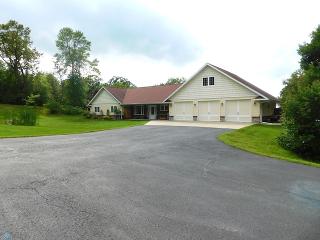view of front of property featuring aphalt driveway, a garage, and a front yard