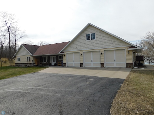 view of front facade with stone siding, driveway, and a front lawn