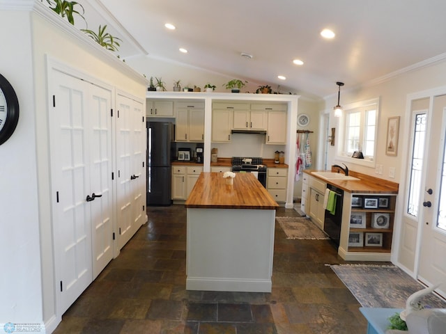 kitchen featuring butcher block countertops, a sink, lofted ceiling, black appliances, and crown molding