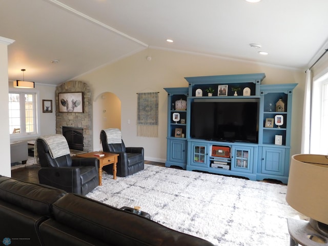 living area featuring arched walkways, a fireplace, crown molding, and vaulted ceiling