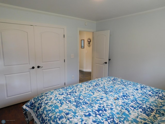 bedroom with a closet, dark wood-style flooring, baseboards, and ornamental molding