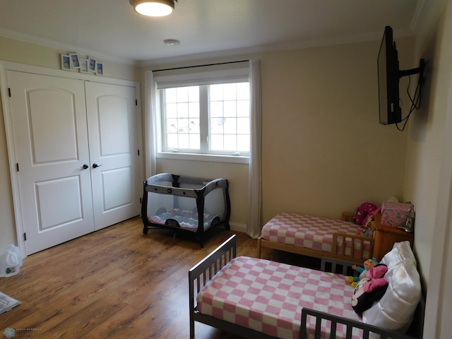 bedroom featuring ornamental molding, a closet, and wood finished floors