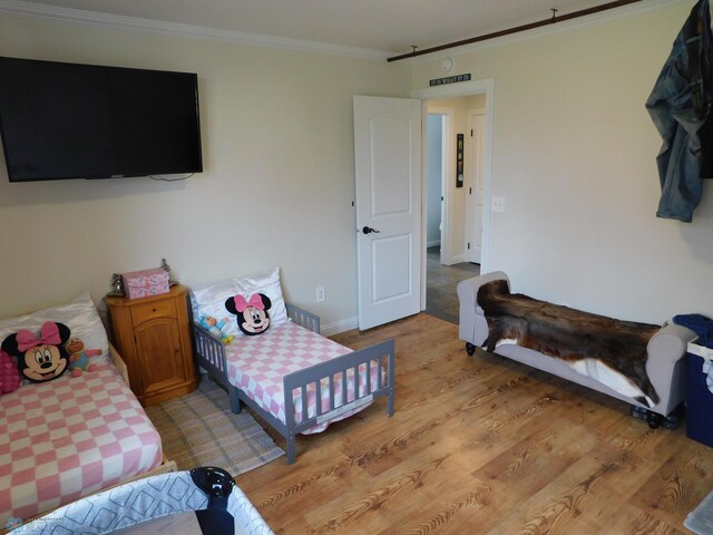 bedroom featuring ornamental molding, light wood-style flooring, and baseboards