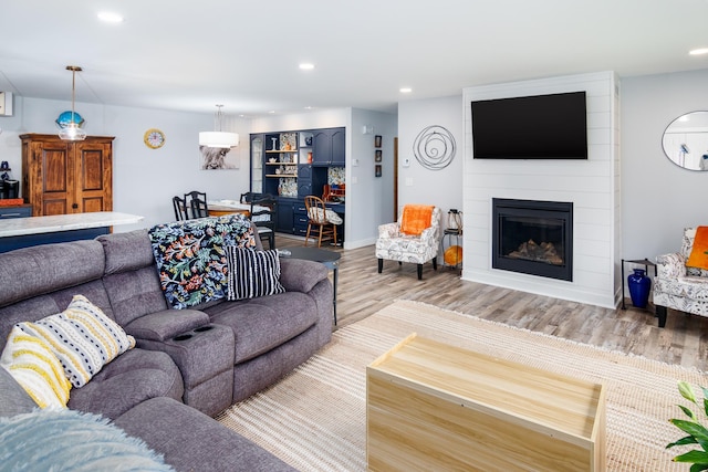 living room with recessed lighting, a large fireplace, and wood finished floors