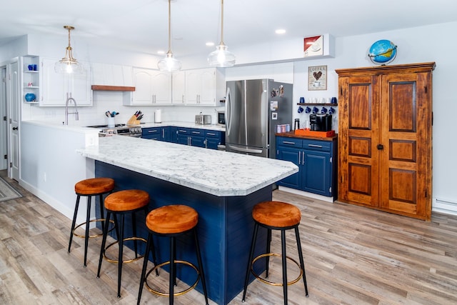 kitchen with a breakfast bar area, appliances with stainless steel finishes, and blue cabinetry