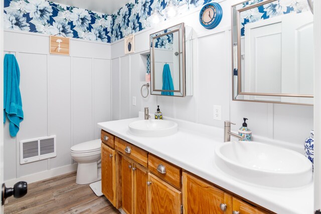 bathroom featuring double vanity, wood finished floors, a decorative wall, and a sink