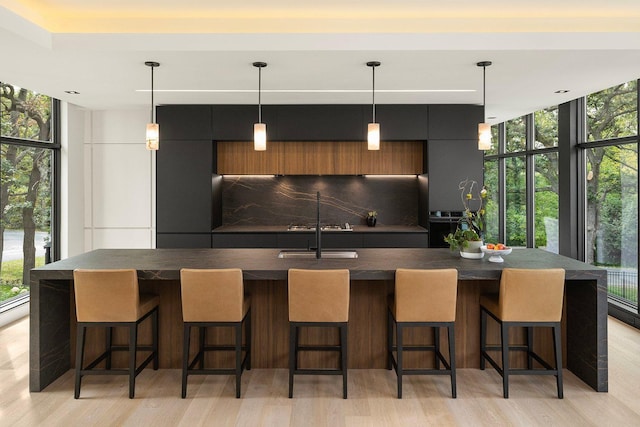 kitchen with modern cabinets, dark countertops, light wood-style floors, and a wall of windows