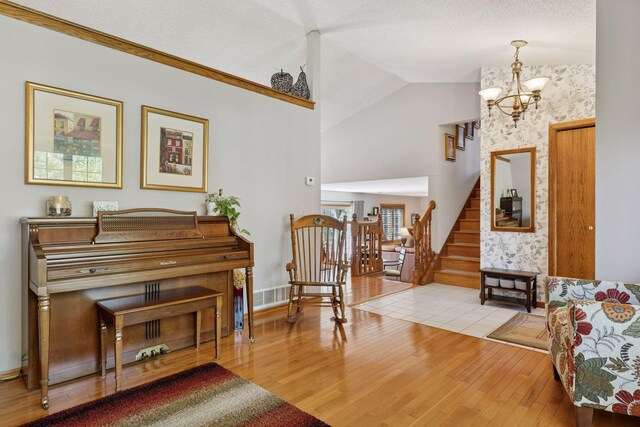 sitting room with hardwood / wood-style floors, a chandelier, stairway, and vaulted ceiling