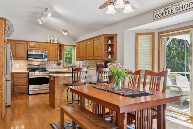 dining area featuring ceiling fan, vaulted ceiling, healthy amount of natural light, and light wood finished floors