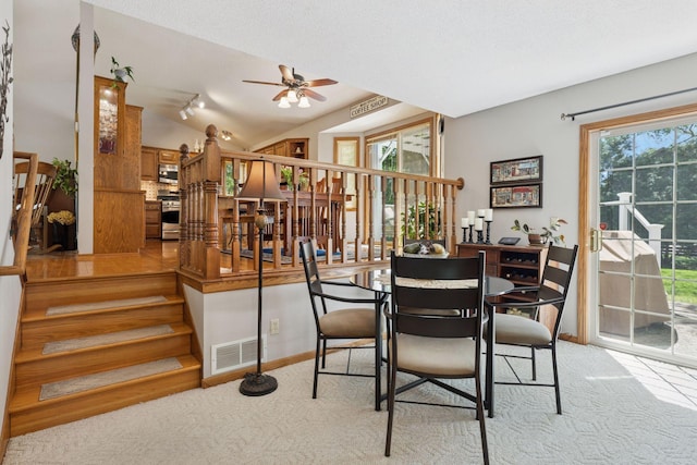 dining area featuring ceiling fan, carpet floors, stairs, lofted ceiling, and baseboards