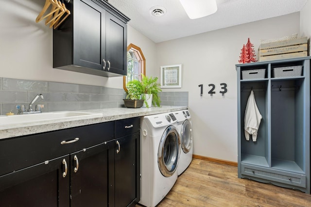 laundry room with cabinet space, washer and dryer, light wood-type flooring, and baseboards