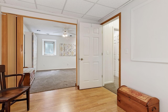 unfurnished room featuring a ceiling fan, light wood finished floors, light carpet, and baseboards