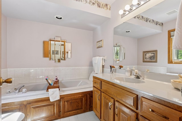 bathroom featuring a garden tub, vanity, and tile patterned flooring