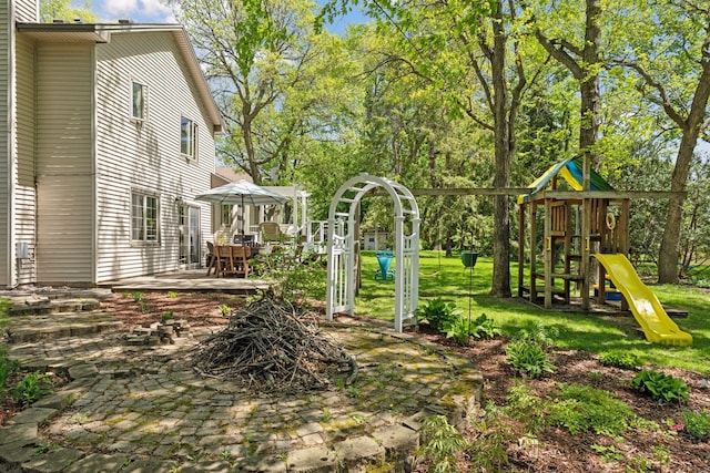 view of green lawn featuring a playground, a patio area, and view of scattered trees