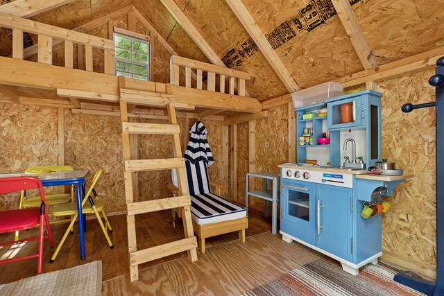 game room with lofted ceiling, a sink, and wood finished floors