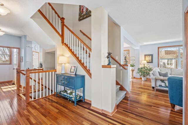 staircase featuring wood-type flooring, a textured ceiling, and baseboards