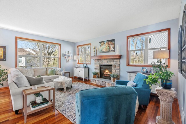 living room featuring a stone fireplace and wood finished floors