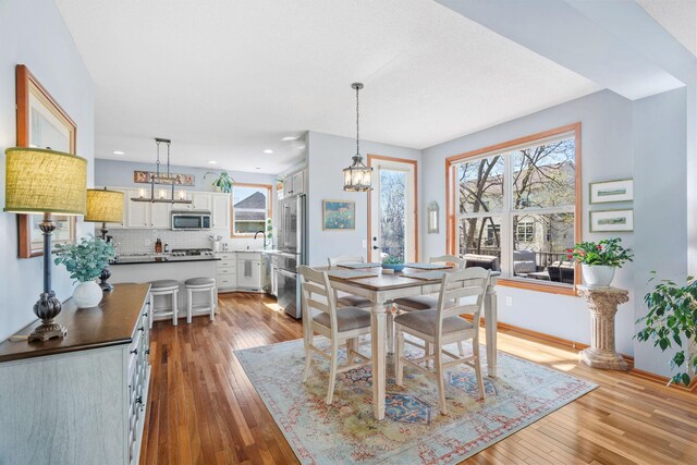 dining area with light wood-style floors, recessed lighting, baseboards, and a chandelier