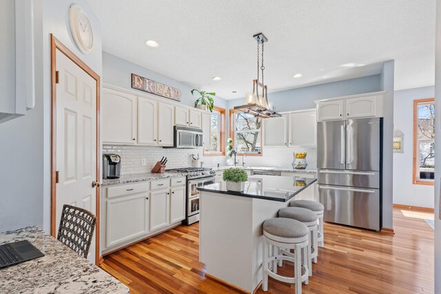 kitchen featuring stainless steel appliances, white cabinetry, tasteful backsplash, and light wood-style floors