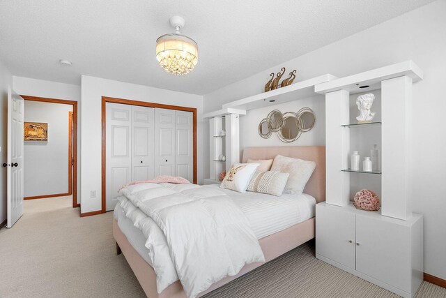 carpeted bedroom with baseboards, a notable chandelier, and a closet
