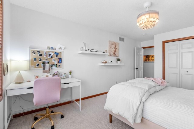 carpeted bedroom featuring visible vents, baseboards, a notable chandelier, and a closet