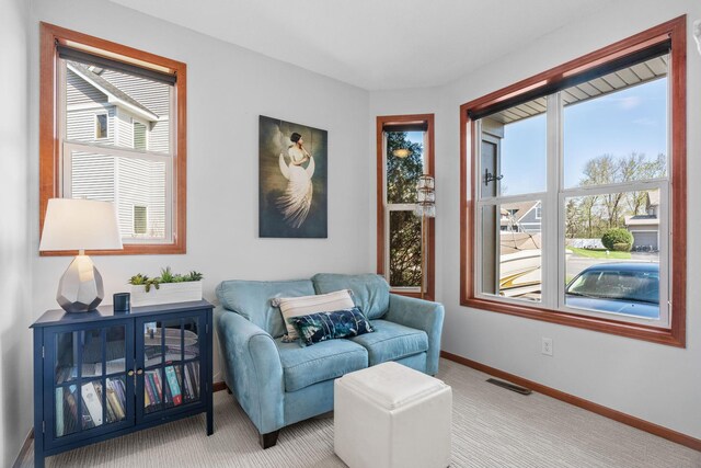 living area featuring visible vents, carpet flooring, and a healthy amount of sunlight