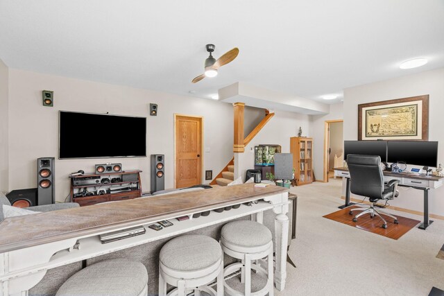 interior space with a kitchen breakfast bar, a ceiling fan, open floor plan, and light colored carpet