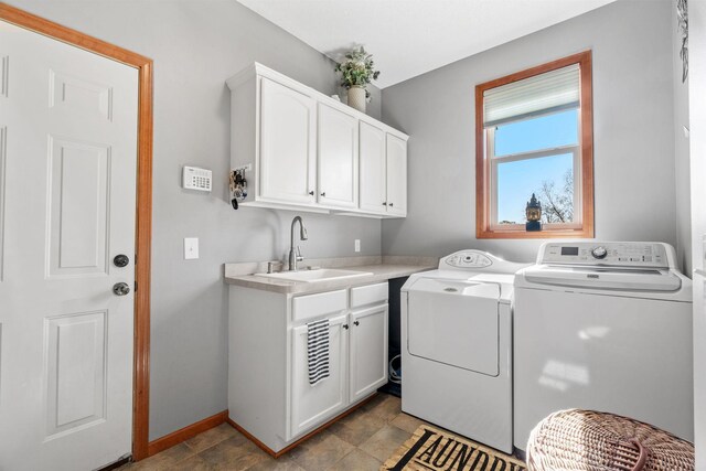 clothes washing area with a sink, separate washer and dryer, baseboards, and cabinet space