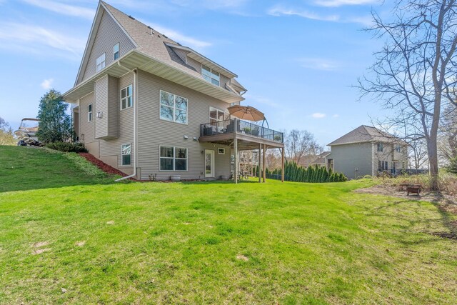 rear view of property featuring a lawn, roof with shingles, and a wooden deck