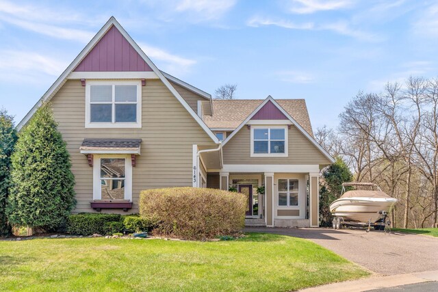craftsman house with roof with shingles, board and batten siding, a front lawn, and aphalt driveway