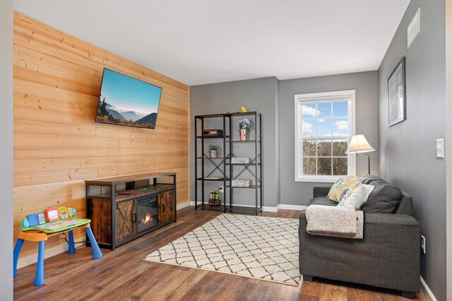 1810 Cherry Cir, Carver, MN 55315 - living area featuring wood walls, wood finished floors, a glass covered fireplace, and an accent wall