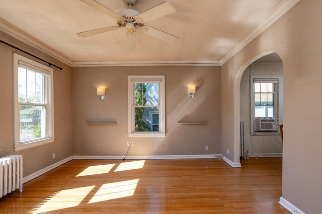 4415 Chowen Ave S Unit 201, Minneapolis, MN 55410 - unfurnished room featuring radiator heating unit, plenty of natural light, wood finished floors, arched walkways, and crown molding
