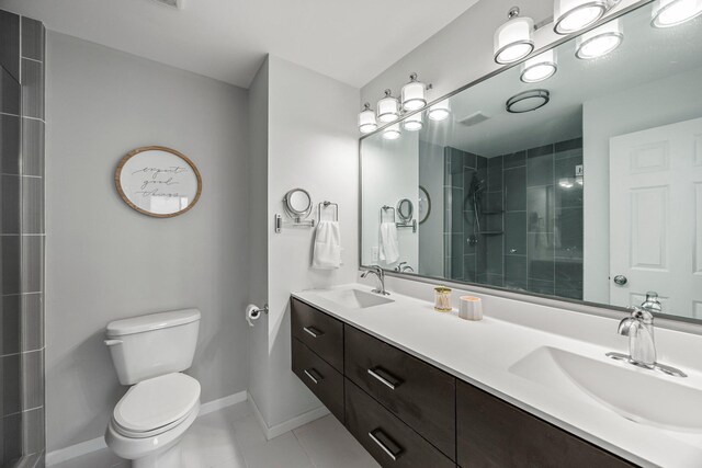14445 Europa Ave, Apple Valley, MN 55124 - bathroom featuring toilet, tiled shower, tile patterned flooring, baseboards, and double vanity
