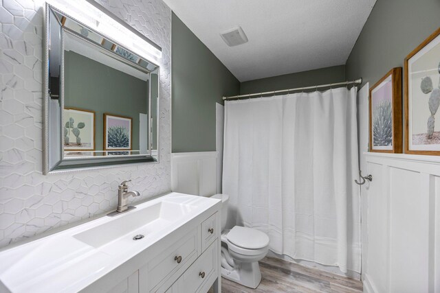 14445 Europa Ave, Apple Valley, MN 55124 - bathroom with wood finished floors, toilet, wainscoting, vanity, and a shower with curtain