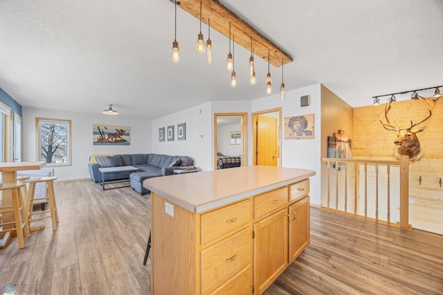 kitchen featuring a center island, a textured ceiling, hanging light fixtures, light wood finished floors, and light countertops