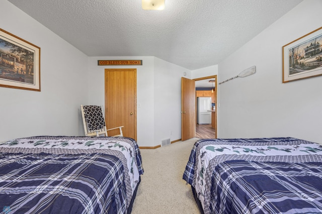 carpeted bedroom featuring freestanding refrigerator, a textured ceiling, baseboards, and visible vents