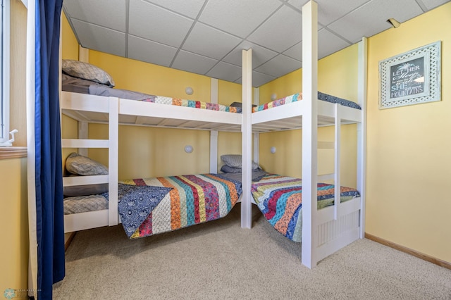 carpeted bedroom featuring baseboards and a paneled ceiling